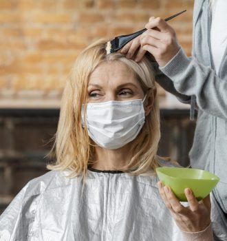woman-with-medical-mask-getting-her-hair-dyed-by-hairdresser-home